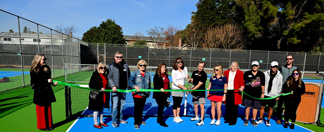 cutting a ribbon on a tennis court